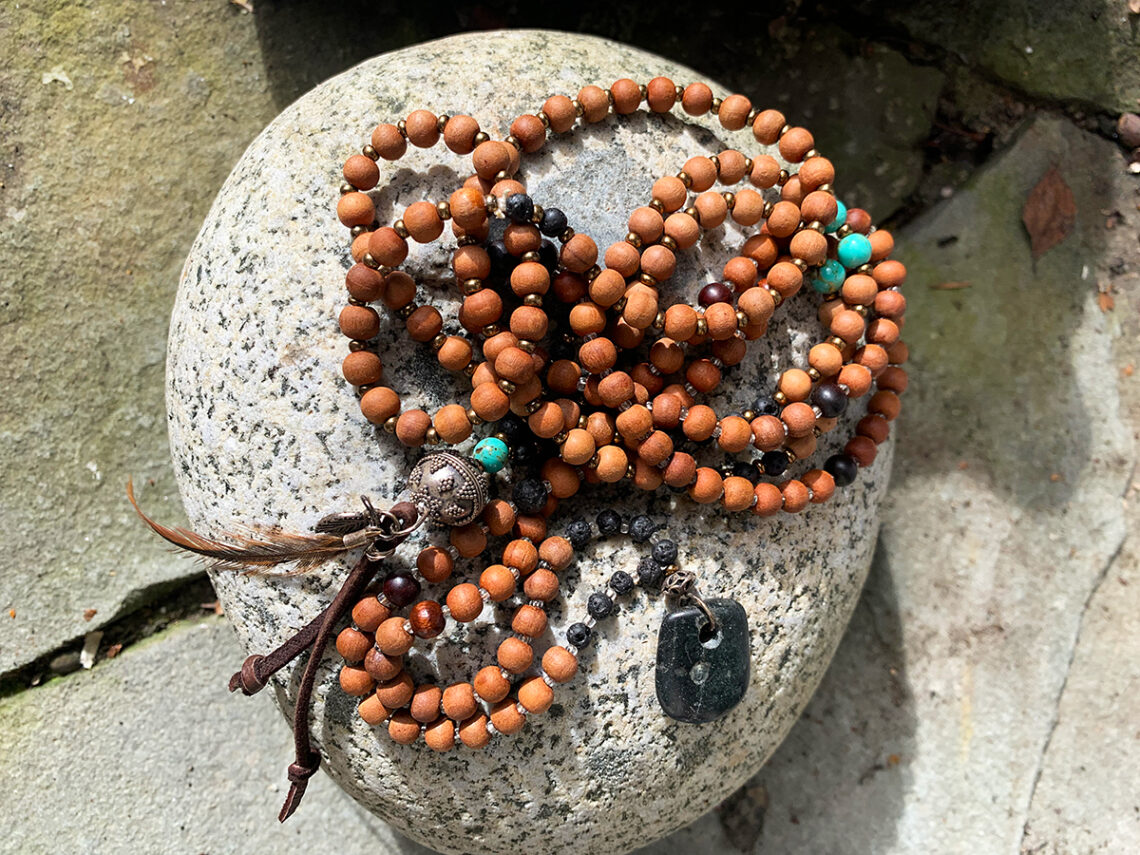 Dava Caldwell art - bead neckless curled up on big rock